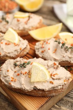 Lezzetli bruschettalar, ezme, limon dilimleri, kekik ve kurutulmuş havuç taneleri ahşap masada, yakın plan.