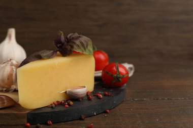 Süt ürünü. Bir parça peynir, domates, fesleğen, biber ve sarımsak, ahşap masa, yakın plan. Metin için boşluk