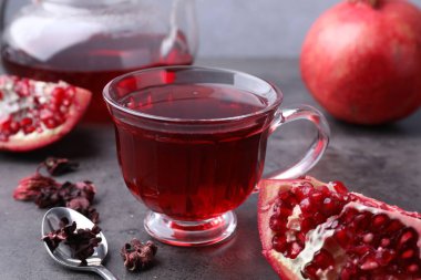 Aromatik nar çayı, taze meyveler ve gri masada kuru roselle sepals, yakın plan.