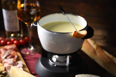 Erimiş peynir, şarap ve ahşap masada atıştırmalıklarla fondü tenceresi (caquelon)