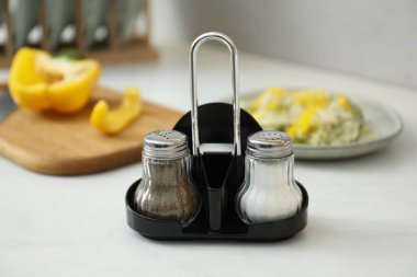 Beyaz masadaki baharatlı tuzluklar ve biberlikler, yakın plan.