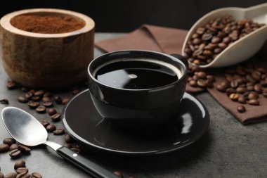 Kahve fincanda, fasulye de gri masada, yakın plan.