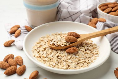 Yulaf gevreği, badem sütü ve fındıklar beyaz mermer masada, yakın plan.