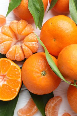 Taze mandalina ve yeşil yapraklar beyaz ahşap masada, düz yatıyordu.