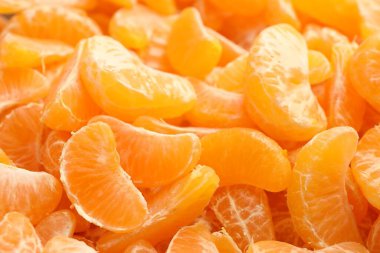 Arka plan olarak birçok olgun soyulmuş mandalina, yakın plan