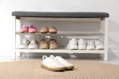 Beyaz duvarın yanında farklı ayakkabıları olan bir ayakkabı deposu.