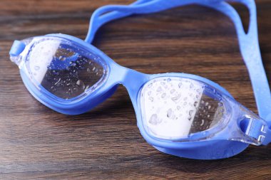 Su damlaları ile yüzme gözlükleri ahşap masaya, yakın plan