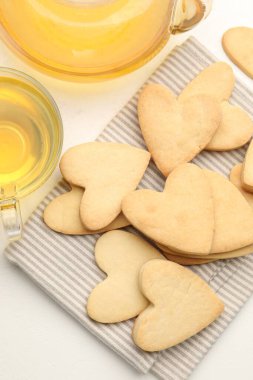 Lezzetli kalp şekilli kurabiyeler ve çay beyaz masada, düz yatıyordu.