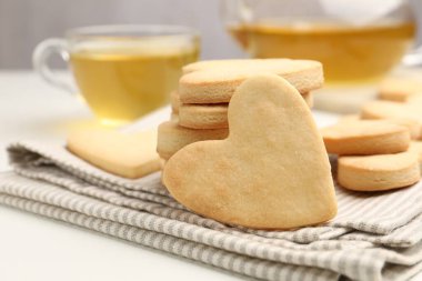 Lezzetli kalp şeklinde kurabiyeler ve çay beyaz masada, yakın plan.