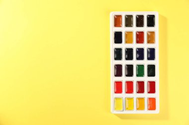 Sarı arka planda suluboya palet, üst manzara. Metin için boşluk