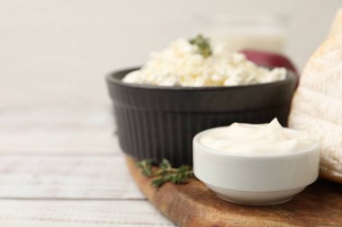 Farklı süt ürünleri ve kekik beyaz ahşap masada, yakın plan. Metin için boşluk