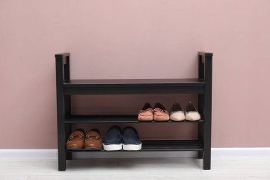 İçerideki tozlu pembe duvarın yanında farklı ayakkabıları olan ayakkabı tezgahı.