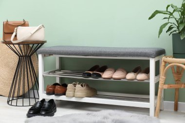 Farklı ayakkabı, aksesuar ve yeşil duvarın yanındaki ev bitkilerinden oluşan ayakkabı deposu.