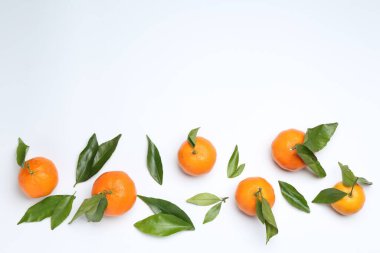 Beyaz arka planda olgun mandalinalar ve yeşil yapraklar. Metin için boşluk