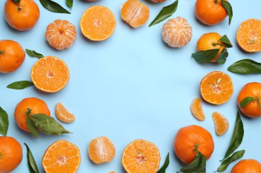 Taze mandalina ve açık mavi arka planda yeşil yapraklar, düz. Metin için boşluk