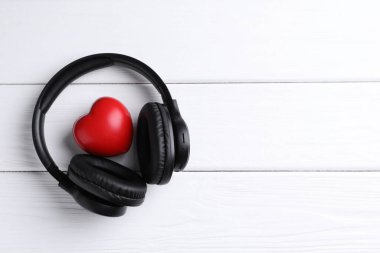 Kulaklıklar ve kalp figürleri beyaz ahşap masa, üst manzara. Metin için boşluk