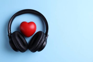 Kulaklık ve kalp figürü açık mavi arka plan, üst manzara. Metin için boşluk