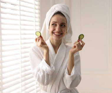 Havluya sarılı güzel bir kadın ve pencerenin yanında salatalık dilimleri.