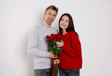 Arka planda gül buketi olan mutlu bir çift. Sevgililer Günü kutlaması