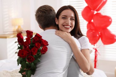 Bir buket gülle erkek arkadaşını kucaklayan mutlu bir kadın. Sevgililer Günü kutlaması