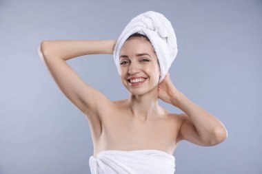 Saçları gri arka planda, havluya sarılı güzel bir kadın.