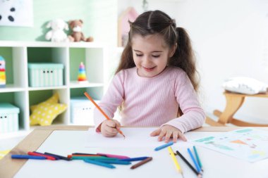 Masada kalemle çizen sevimli küçük kız.