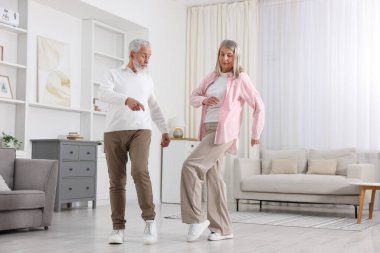 Mutlu yaşlı çift evde dans ediyor.