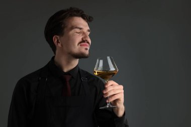 Gri arka planda beyaz şarap kadehi olan profesyonel şarap garsonu.
