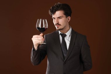 Kahverengi arka planda kırmızı şarap kadehi olan profesyonel şarap garsonu.
