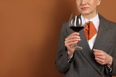 Profesyonel şarap garsonu kahverengi arka planda şarap tadıyor, yakın plan. Metin için boşluk