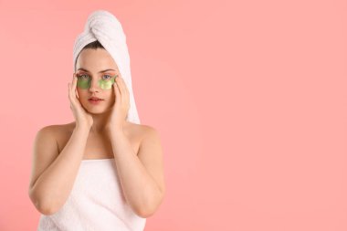 Pembe arka planda havluya sarılı göz bandı olan bir kadın. Metin için boşluk