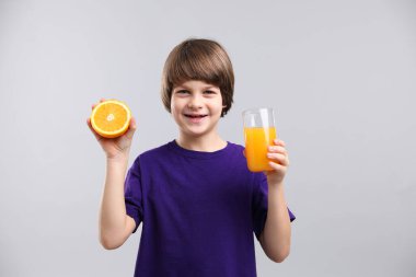 Açık gri arka planda taze portakal suyu ve meyveli çocuk.