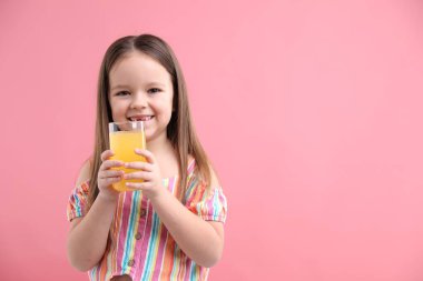 Pembe arka planda bir bardak portakal suyu olan küçük kız, mesaj için yer var.