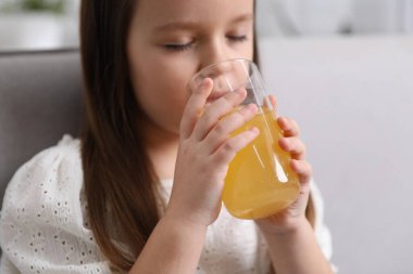 Küçük kız evde portakal suyu içiyor, yakın plan.