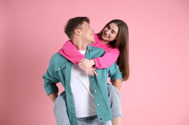 Mutlu çift pembe arka planda birbirlerine sarılıyorlar.