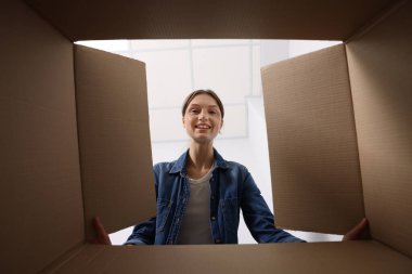 Kadın içerideki karton kutuya bakıyor, içerideki paketi görüyor.