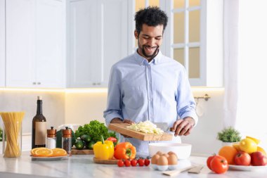 Adam mutfaktaki masada kabın içine kesilmiş lahana ekliyor. Metin için boşluk