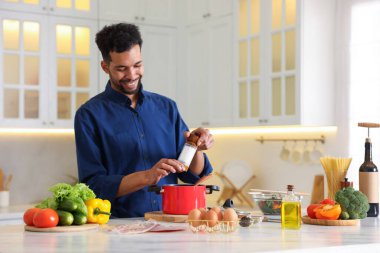 Adam mutfaktaki masaya tuz ekliyor.