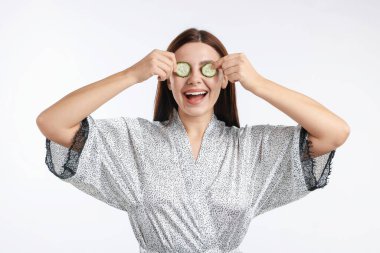 Beyaz arka planda salatalık dilimleri olan bir kadın.