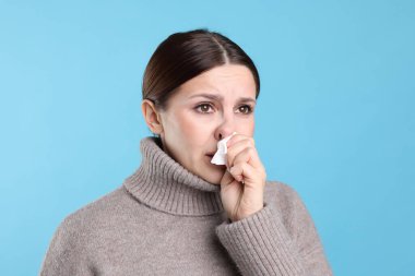 Açık mavi arka planda burnu akan bir kadın. Soğuk Semptom