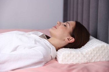 Evde ortopedik yastıkla uyuyan genç bir kadın. Sağlıklı duruş