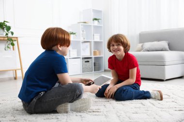 Evde tabletleri olan sevimli kardeşler.