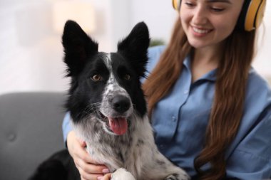 Evdeki kanepede sevimli köpeğiyle gülümseyen bir kadın.