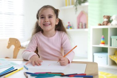 Masada kalemle çizen sevimli küçük kız.