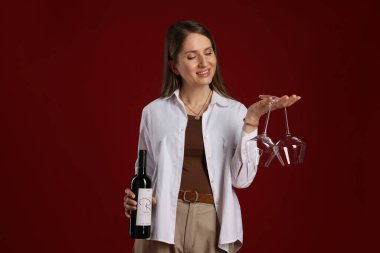 Kırmızı arka planda şarap ve gözlüklü profesyonel şarap garsonu.