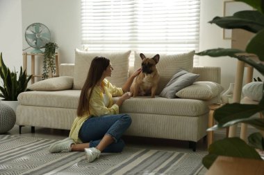 Evdeki kanepenin yanında tatlı köpeği olan bir kadın.