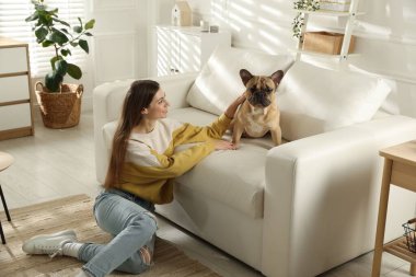 Evdeki kanepenin yanında tatlı köpeği olan bir kadın.