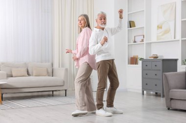 Mutlu yaşlı çift evde dans ediyor.