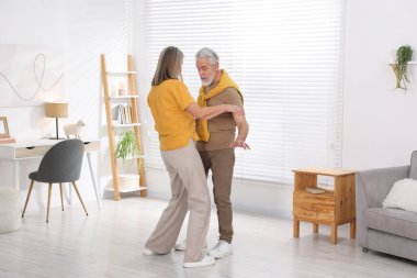 Mutlu yaşlı çift evde dans ediyor.