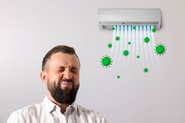 İçerideki klimanın kötü kokusundan suratını buruşturan adam. Cihazdan uçan bakterilerle hava akışı